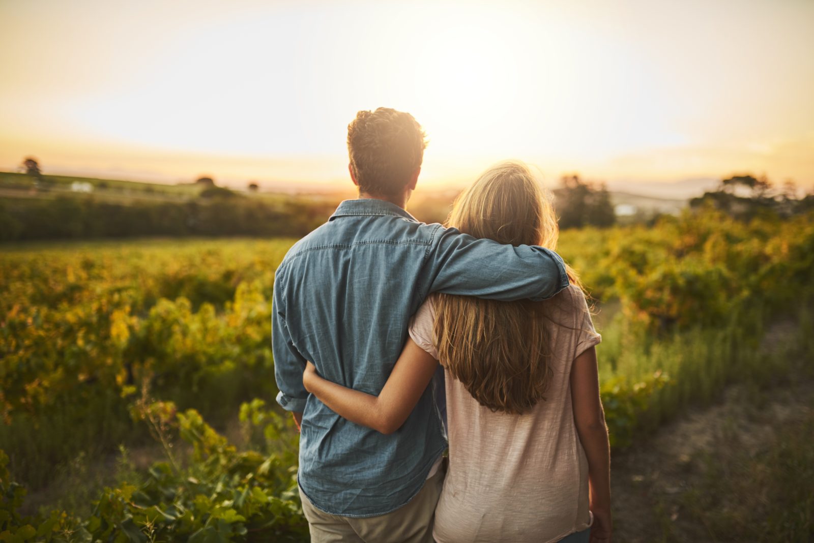 A couple watching the sunset together over a vineyard