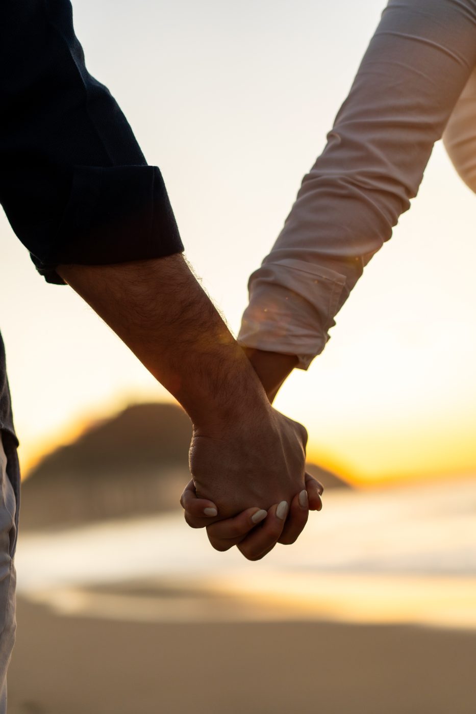 A couple holding hands as they watch the sunset